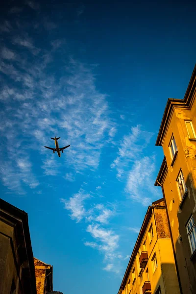 ジェット旅客機がソフィア ブルガリアのダウンタウンの通り上空を飛んでいます 青い空に白い雲 古い茶色の煉瓦住宅 日没で撮影した画像 — ストック写真
