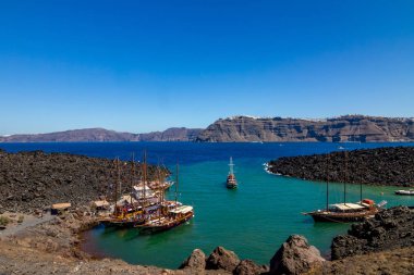 Nea Kameri volkanik ada bağlantı noktası görünümü birkaç turist tekneleri, Santorini, Yunanistan ile. Derin deniz kristal suları ve çarpıcı siyah caldera doğru şaşırtıcı gündüz görünümü
