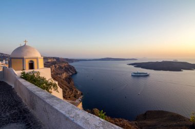Santorini üzerinde yükseltilmiş romantik günbatımı sahne. Yukarıdaki üzerinden, Fira, Yunanistan. Şaşırtıcı altın saat görünümden genel yolu yürüyüş caldera yanardağ doğru. Kısa bir süre önce günbatımı, kilise görüntü