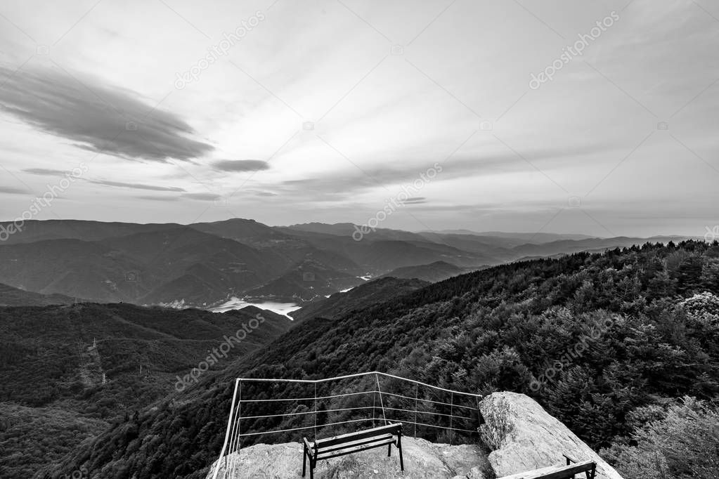 Calm scenery springtime black and white landscape, high altitude observation deck view with picturesque rocks and wooden bench in Rhodope mountain near village of Ravnogor, Pazardzik county, Bulgaria