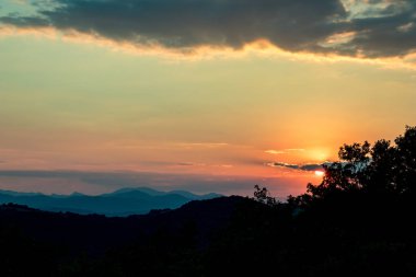 Güneş bulutların arkasına renkli yaz günbatımı gizleme