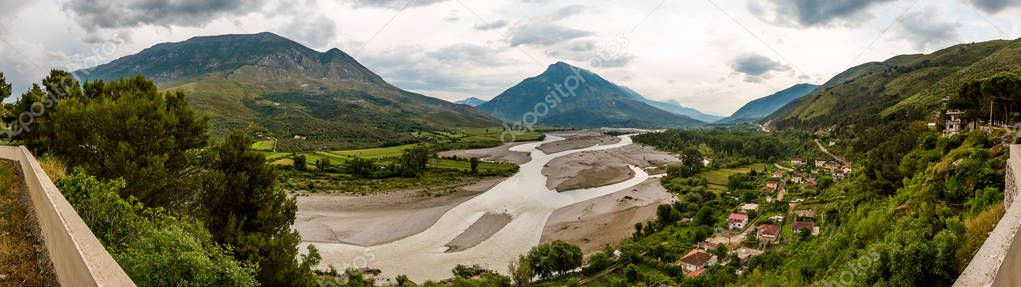 Stitched panorama of Mat river or Lumi, Albania, cloudy springtime day landscape with green foliage and beautiful mountains