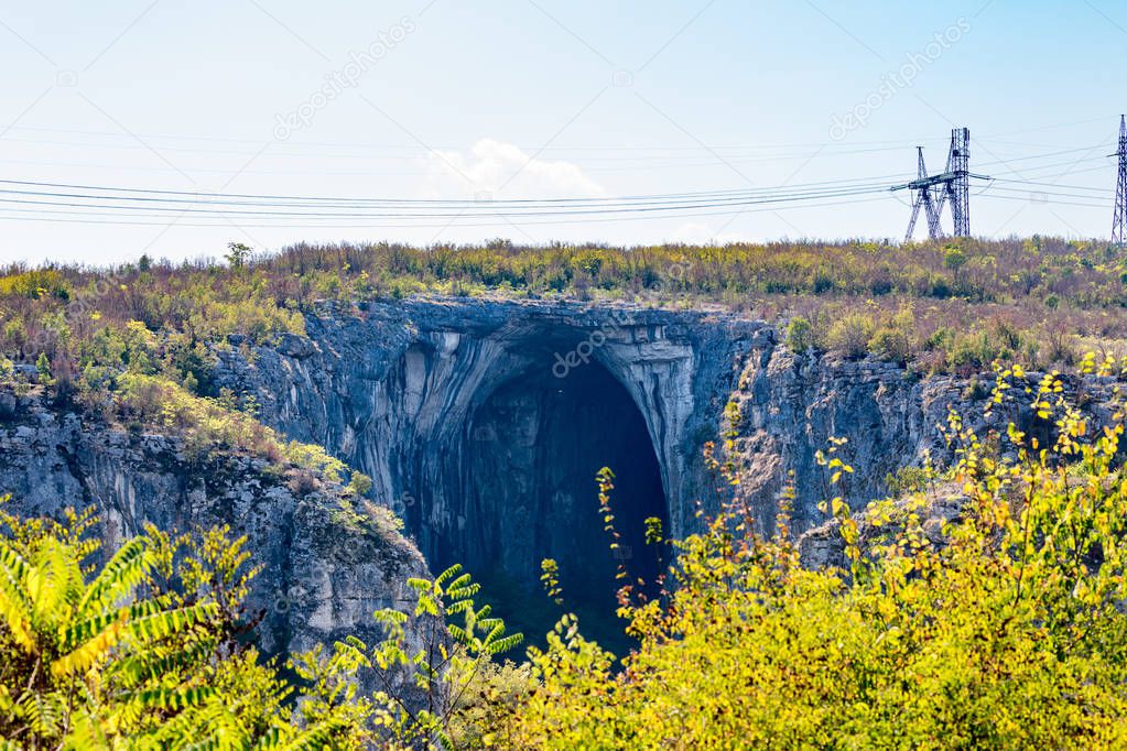 Huge entrance of Bulgarian cave, electric poles