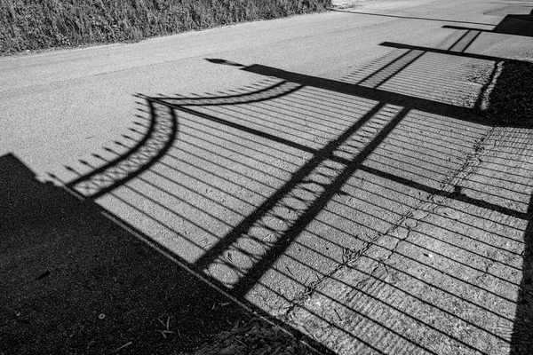 Σκιά του φράκτη των κήπων στο βρώμικο δρόμο — Φωτογραφία Αρχείου