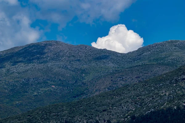 White puffy cloud pops out from behind mountain