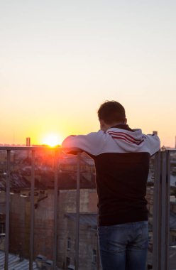 Genç adam şehir peyzaj gün batımını izlemek