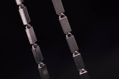 Karanlık bir arka plan üzerinde bir metal/gümüş kolye.