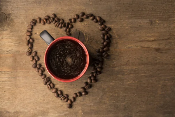 A coffee bean heart with a coffee mug in the middle