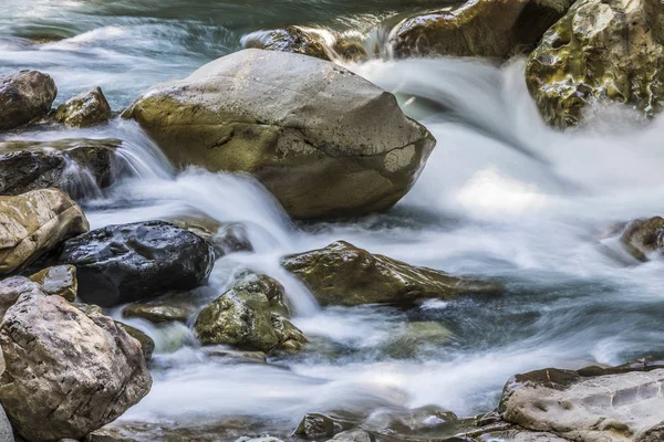 Uzun pozlama boyunca akan bir nehrin kayalar