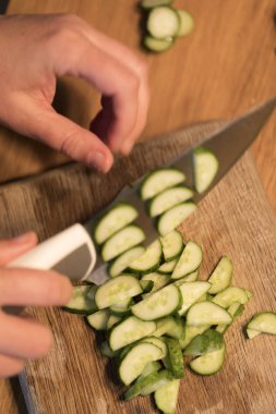 Birisi bir salatalık bir kesme tahtası üzerinde kesme