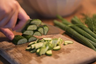 Birisi bir salatalık bir kesme tahtası üzerinde kesme