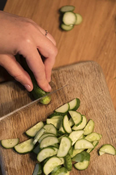 Someone cutting a cucumber on a cutting board