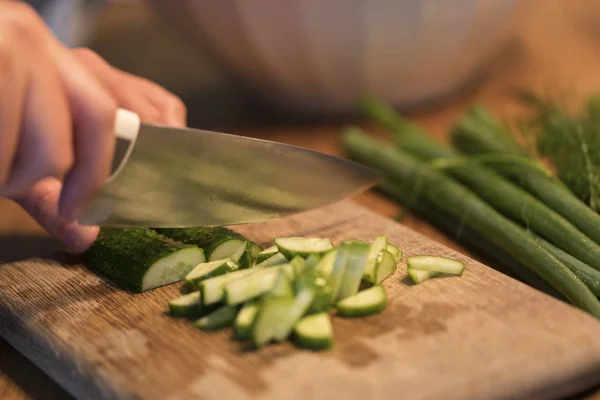 Someone cutting a cucumber on a cutting board