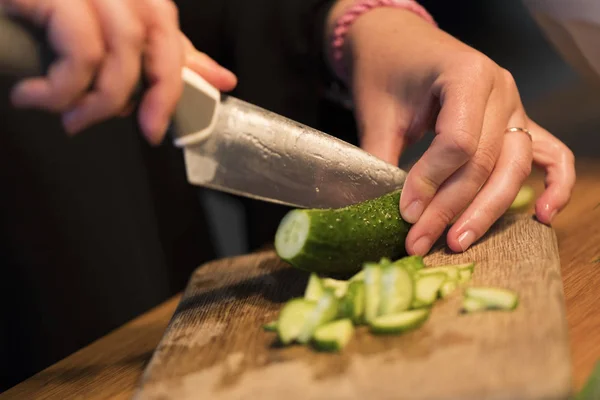 Someone cutting a cucumber on a cutting board