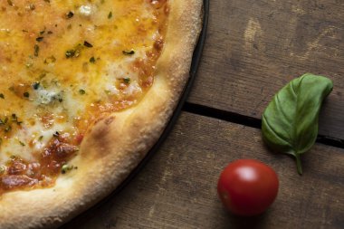 Fesleğen yaprağı ve domatesli margherita pizzasının bir parçası.