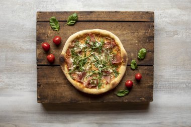 Et, peynir, kurutulmuş domates ve ahşap bir yüzeyde ekmekle jambonlu pizza.