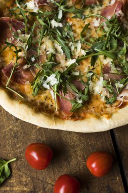 Et, peynir, garnitür ve ahşap bir yüzeyde ekmekli prosciutto pizzasının bir parçası.