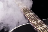 Součást černého klasická kytara v kouři na černém pozadí