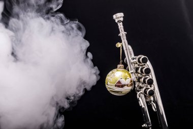 Bir Noel süs duman siyah bir arka plan ile piccolo trompet bir gümüş kaplama