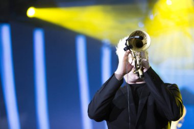 Bir konserde sahne ışıkları içinde belgili tanımlık geçmiş ile gerçekleştirme trompetçi