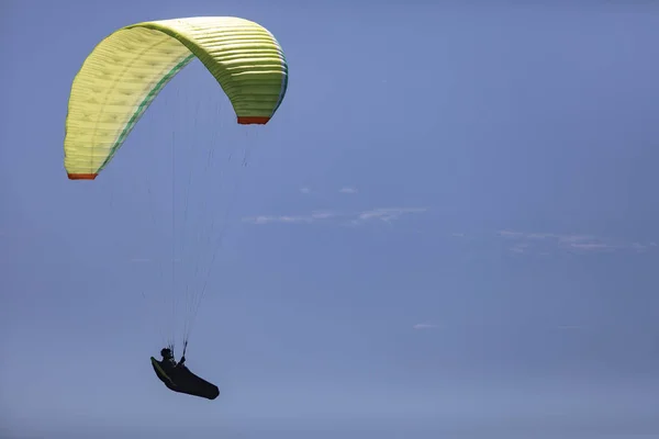 A person with a parachute up in the air on a blue sky