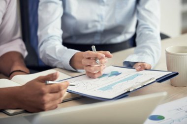 Erkek ve kadın grafikleri kağıt belge üzerinde tartışırken kırpılmış görüntü 