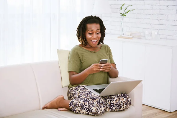 Emocionado Mujer Afroamericana Leyendo Mensaje Teléfono Inteligente Sentado Sofá Con —  Fotos de Stock