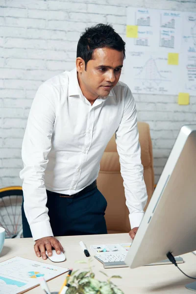 オフィスの机に立って コンピューターで作業して半ばの大人のインドのビジネスマン — ストック写真