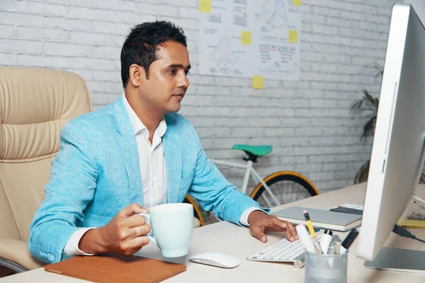 Pewni Indyjski Biznesmen Siedząc Przy Biurku Picia Kawy Przy Użyciu — Zdjęcie stockowe