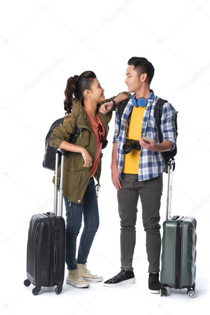 Adorable Asian couple looking at each other with wide smiles while standing in studio 