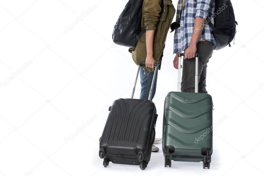 cropped image of tourists pulling heavy suitcases, isolated on white background