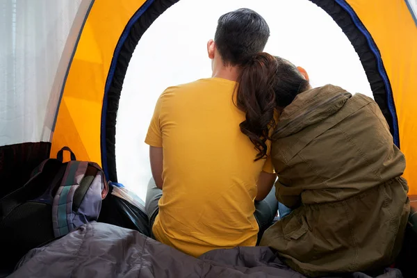 Back view of loving young couple sitting in tent