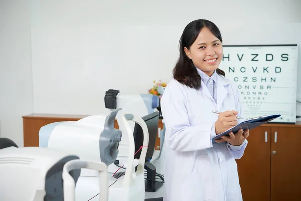 Alegre Asiático Oftalmólogo Médico Mujer Blanco Capa Celebración Portapapeles Habitación —  Fotos de Stock