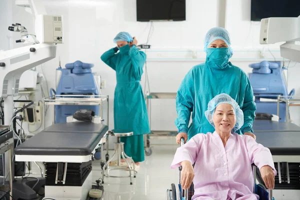 Asyalı Doktorlarla Tekerlekli Sandalyede Asyalı Olgun Kadın Ameliyathane Içinde — Stok fotoğraf