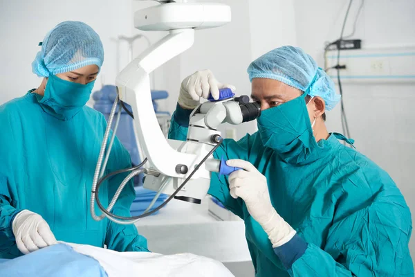 Médicos Asiáticos Focados Olhando Para Microscópio Operacional — Fotografia de Stock