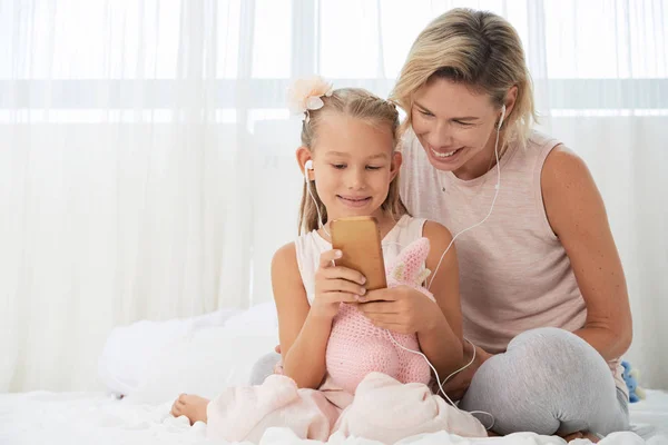 Mère Fille Souriantes Dans Les Écouteurs Regardant Sur Écran Smartphone — Photo