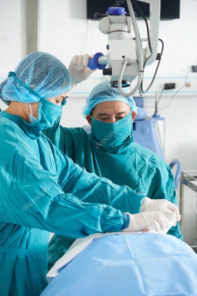 Asian professional doctors preparing patient for surgery in operating room