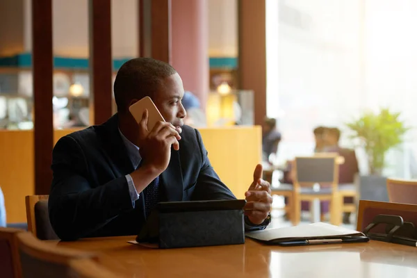 非裔美国商人坐在咖啡馆和电话交谈 — 图库照片