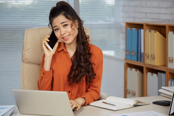 ノート パソコンと彼女の職場のテーブルで電話で呼び出して若いアジア ビジネス女性の肖像 — ストック写真