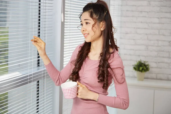 Mooie Peinzende Vrouw Houden Van Thee Kopje Kijken Door Blinds — Stockfoto