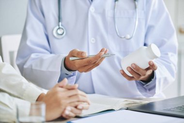 Doktor ilaç şişe tutan ve reçete için bayan hasta vererek resim kırpılmış 
