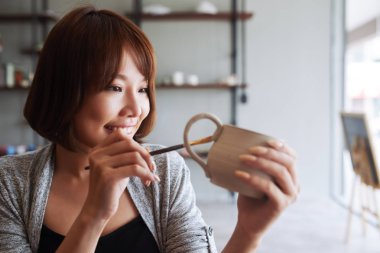 Oldukça mutlu genç Vietnamlı kadın resim kupa fırça ile 