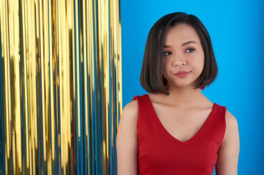 Tarafına bakarak ve altın mavi duvara duran dalgın güzel Asyalı kadın 