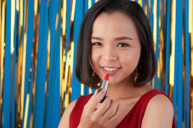 parlak kırmızı mat ruj dudakları uygulama gülümseyen Asyalı kadın 