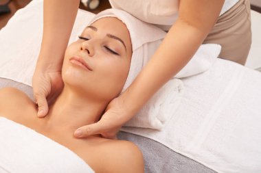 Spa salonda yumuşak havlu genç kadın yatan ve ona boyun masaj rahatlatıcı zevk