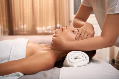 Lüks spa salonda dinlenirken yüzünde sakinleştirici masajdan sonra genç kadın