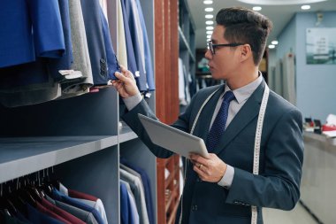 Erkek giyim dükkan sahibi ile ürün yelpazesine kontrol tablet bilgisayar