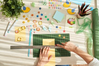 tebrik kartı yaparken cetvel ve kesici bıçak kullanan kadın 