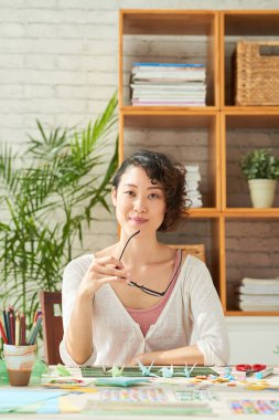 Kameraya bakarak ve gözlük tutan Asyalı kadın 