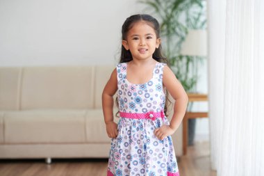 Onu kalça elleri ile ayakta ve kameraya bakarak gülümseyen kız